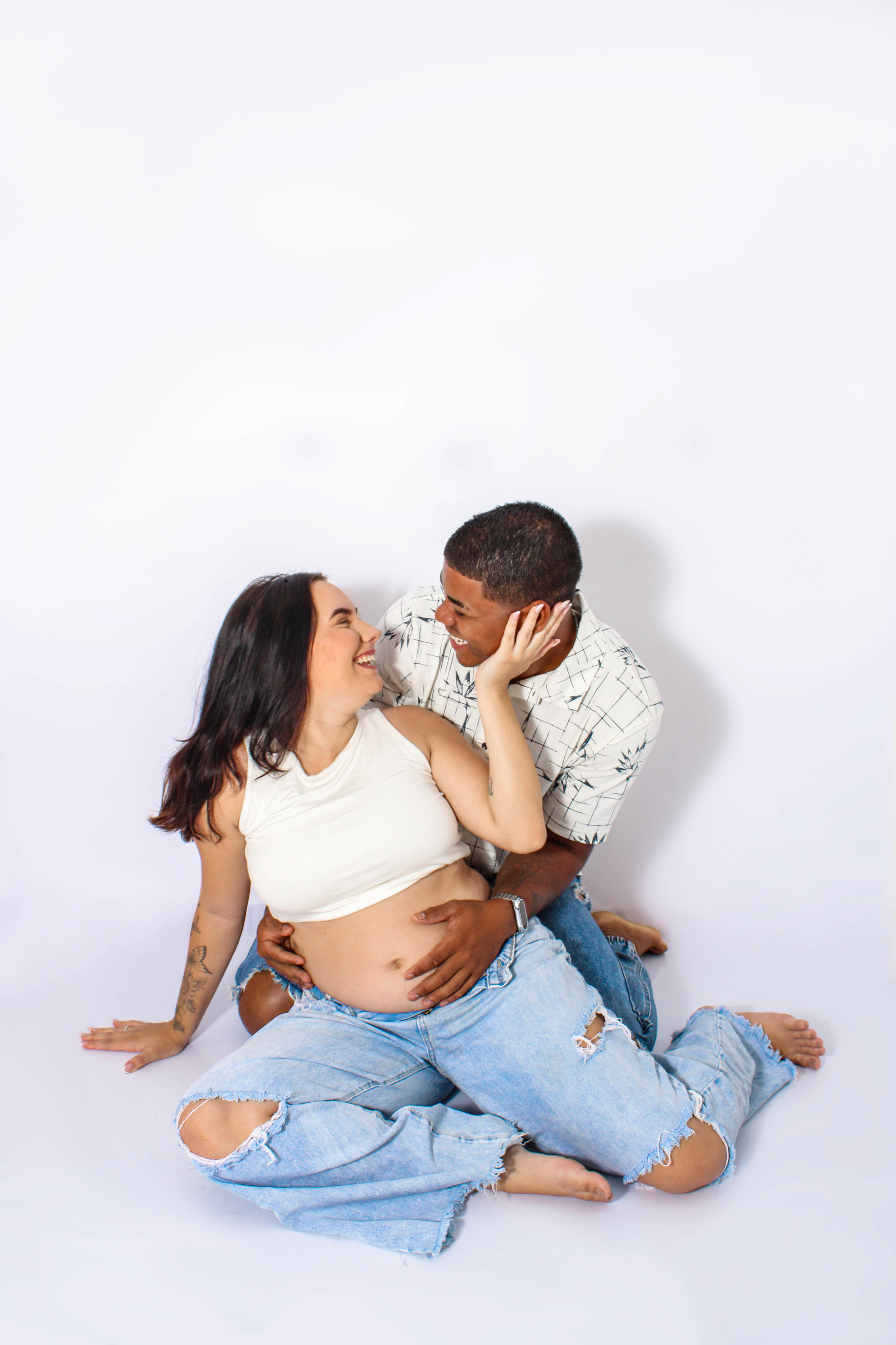 Casal durante ensaio de gestante, a mulher grávida e o parceiro em pose afetuosa.