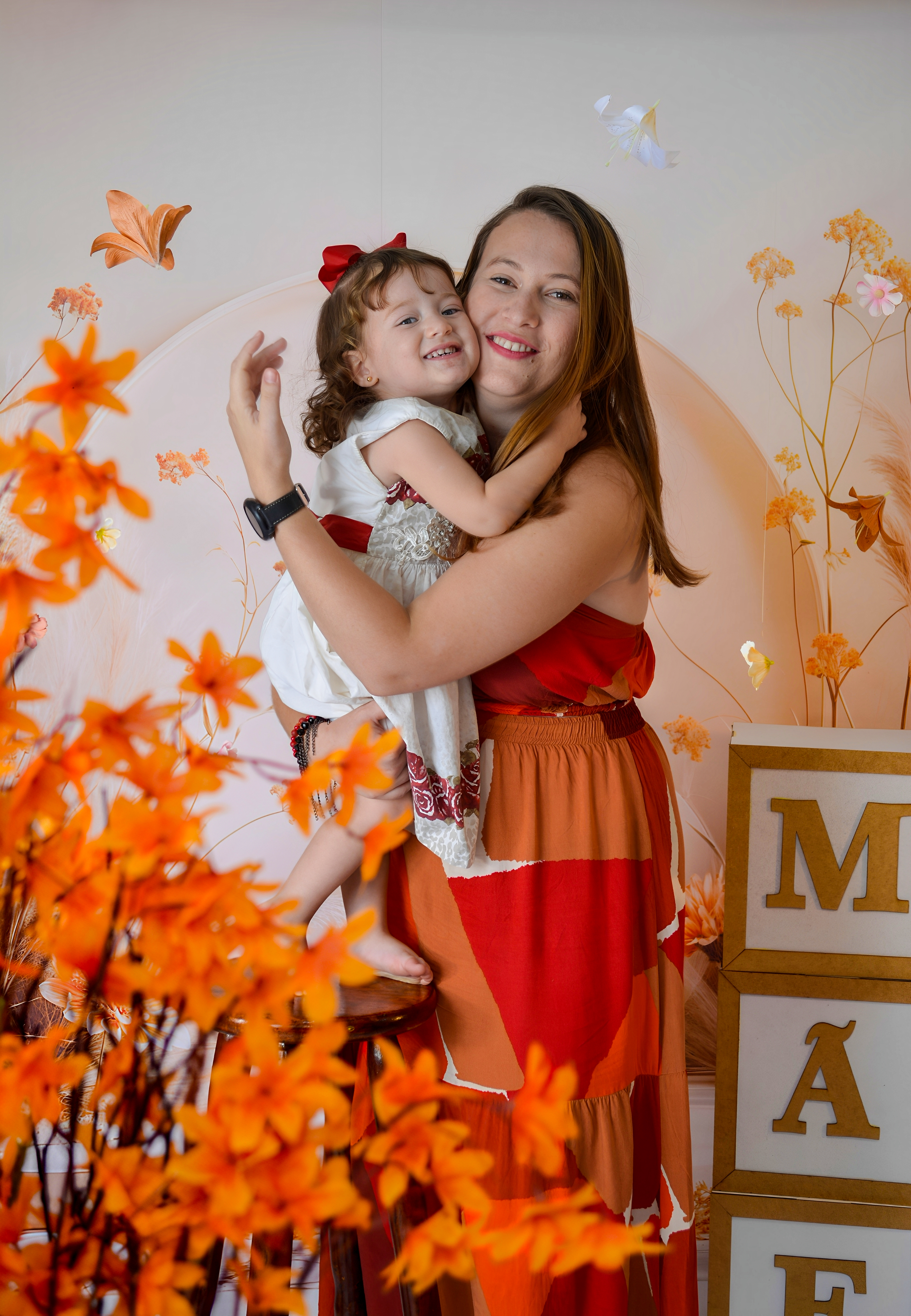 Mãe e filha sorrindo juntas por trás de flores de outono.