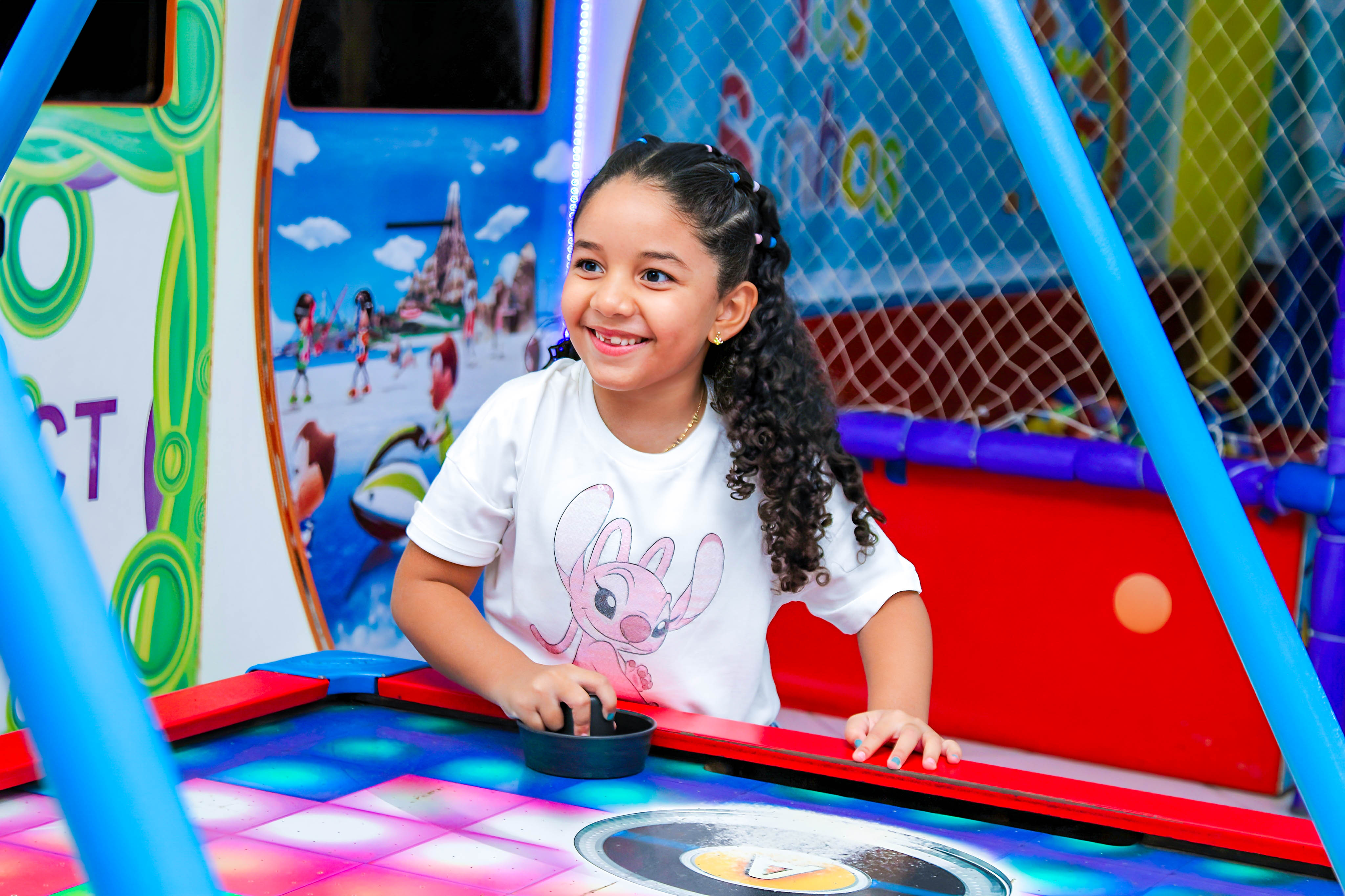 Criança sorrindo enquanto brinca em um brinquedo colorido, durante a festa temática do Stitch.
